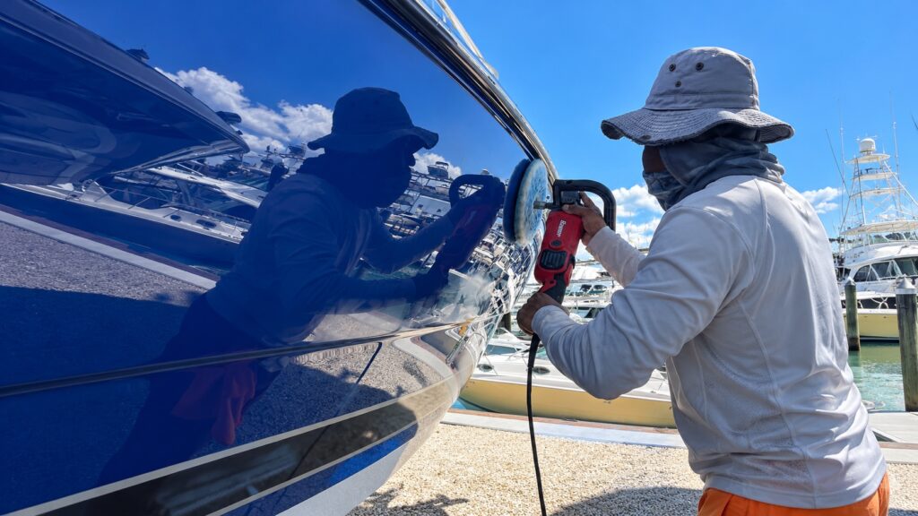 Technician machine-polishing a navy boat hull in Sarasota, FL